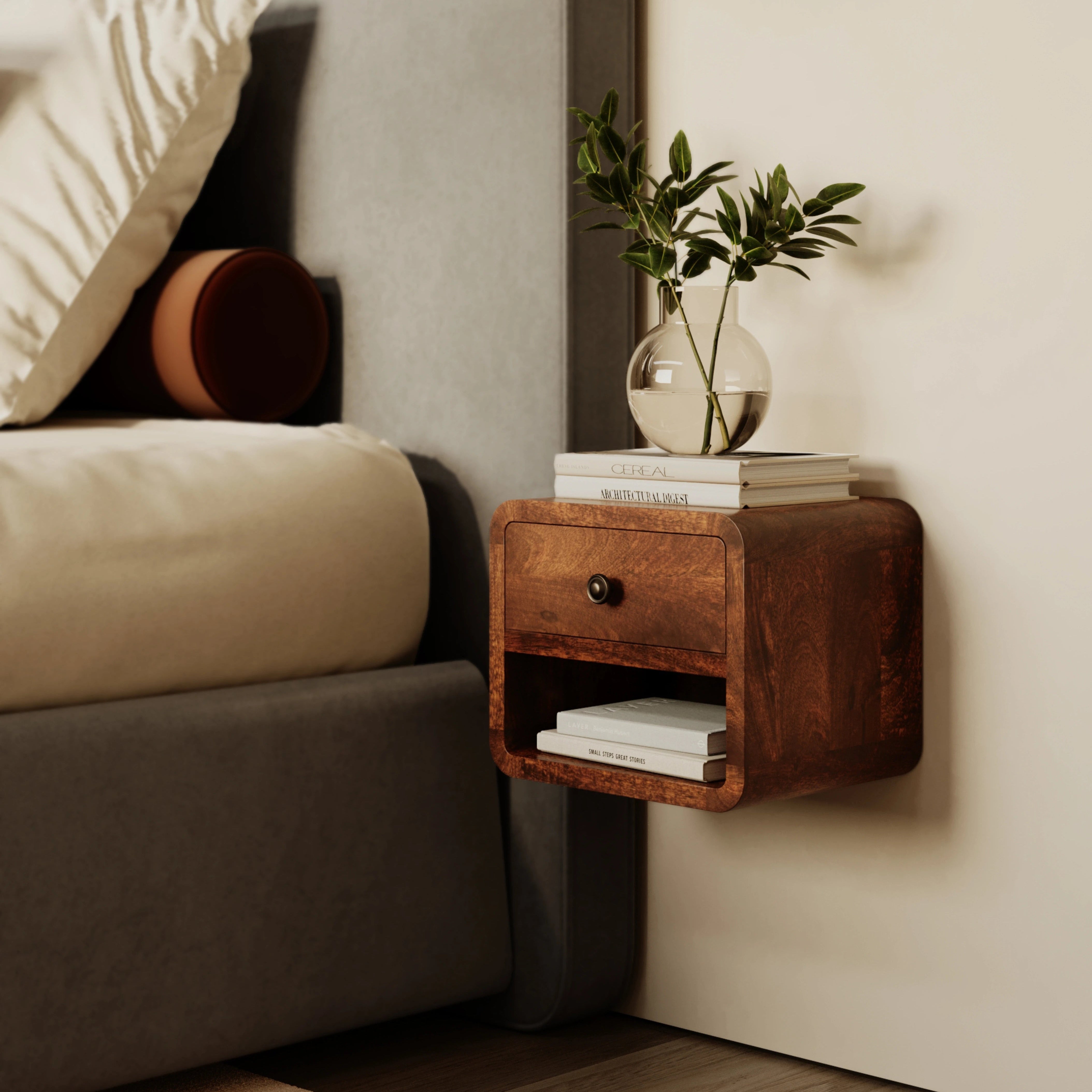 Wooden nightstand with books and a plant next to a bed in a bedroom.